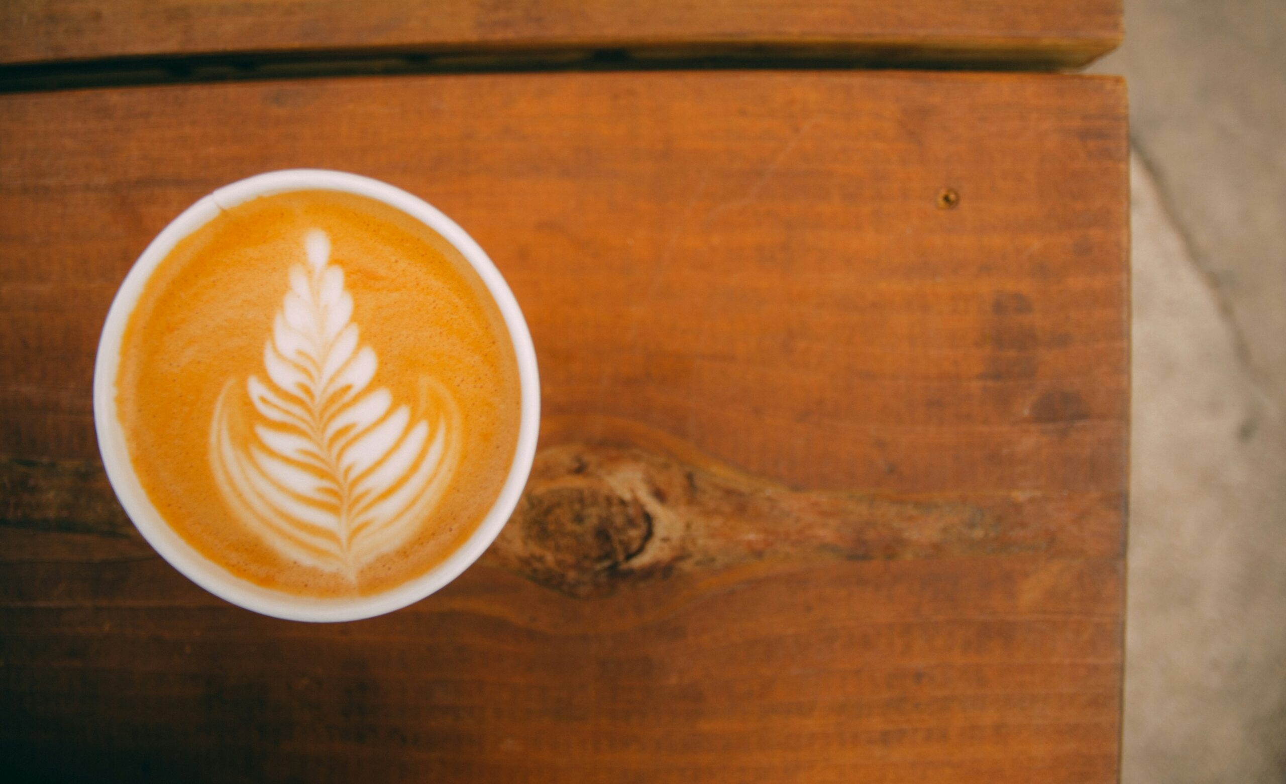 A latte sitting on a wood table at an East Austin coffee shop recommended by the Heywood Hotel.